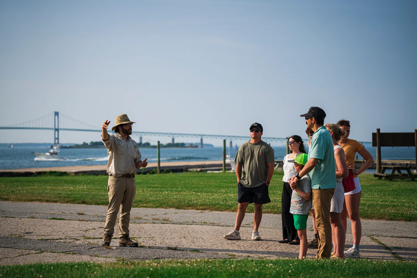 A Fort Adams guide speaking with adults and children beside the waterfront